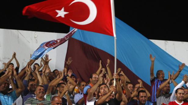 Eine Menschenmenge jubelt mit türkischen Flaggen und Fahnen eines Sportvereins.