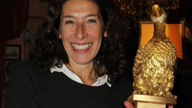 Eine lächelnde Frau hält eine goldene Ente in der Hand.