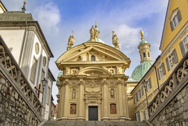 Die Fassade der Grazer Stadtpfarrkirche mit Statuen und grüner Kuppel.
