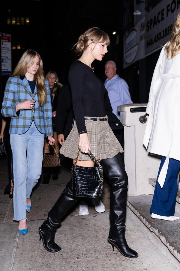 Taylor Swift mit schwarzen Overknee-Stiefeln im Straßenstil.