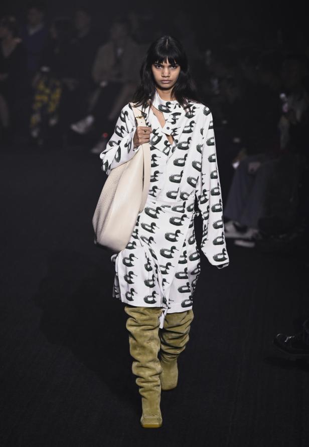 Ein Model auf dem Laufsteg in einem Entenmuster-Kleid und beigen Stiefeln von Burberry, Herbst/Winter 2023.