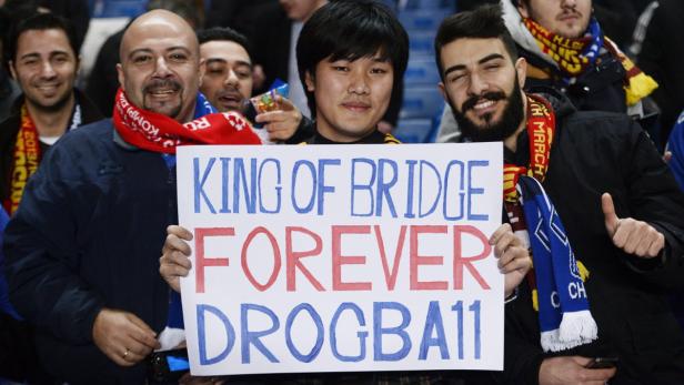 Eine Gruppe von Fußballfans hält ein Schild mit der Aufschrift „King of Bridge Forever Drogba11“.