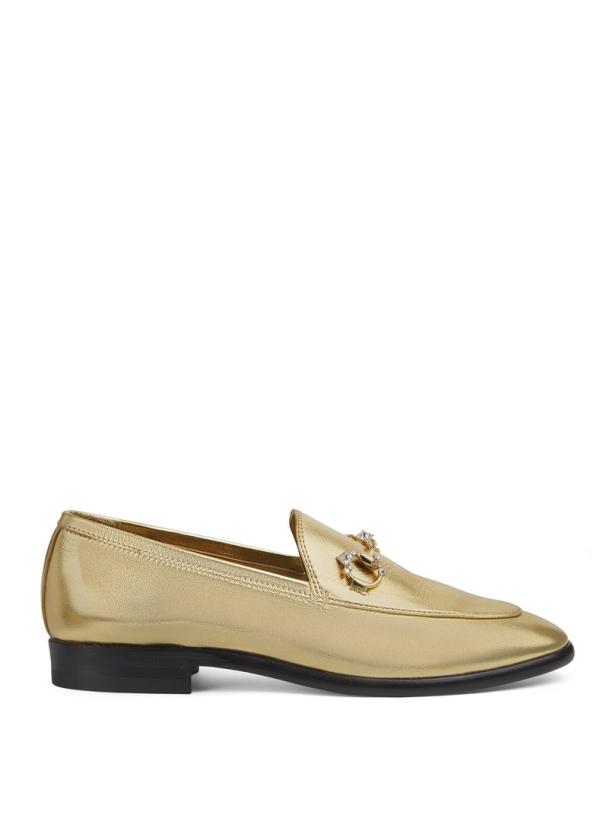 Ein goldener Loafer mit einem Schmuckstück auf dem Oberleder.