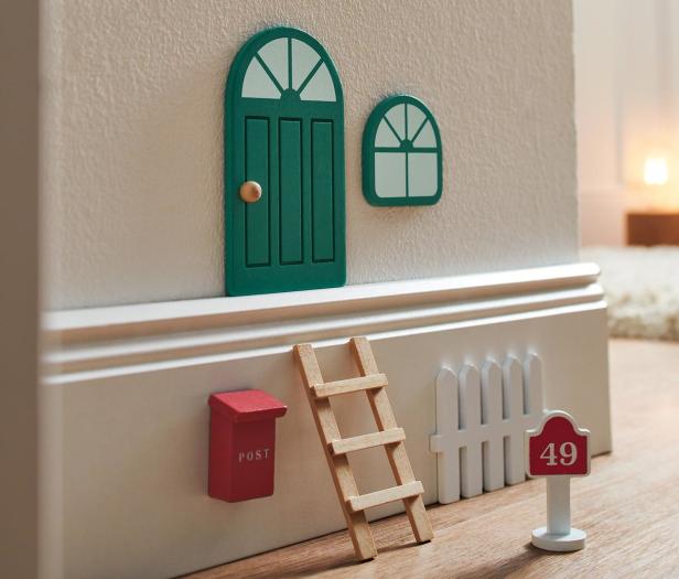 Eine Miniatur-Fassade mit Tür, Fenster, Briefkasten, Leiter, Zaun und Hausnummer 49.