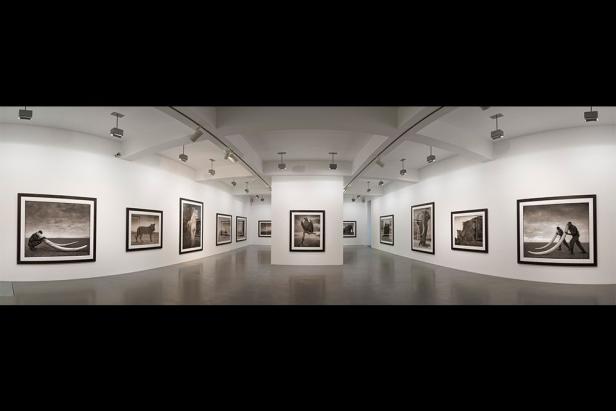 Eine Ausstellungshalle mit Schwarzweißfotografien an den Wänden.