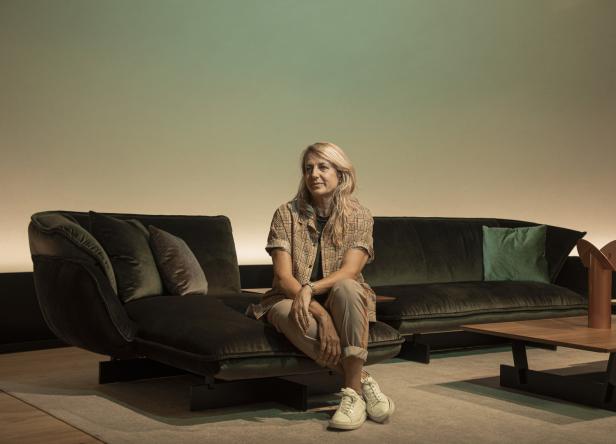 Eine Frau sitzt auf einem grünen Sofa in einem modern eingerichteten Raum.