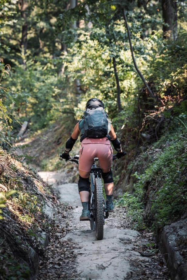 Eine Frau fährt mit einem Mountainbike auf einem Waldweg.