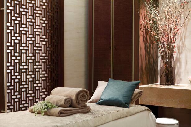 Ein Spa-Bett mit Handtüchern, Kissen und einem Blumenarrangement.