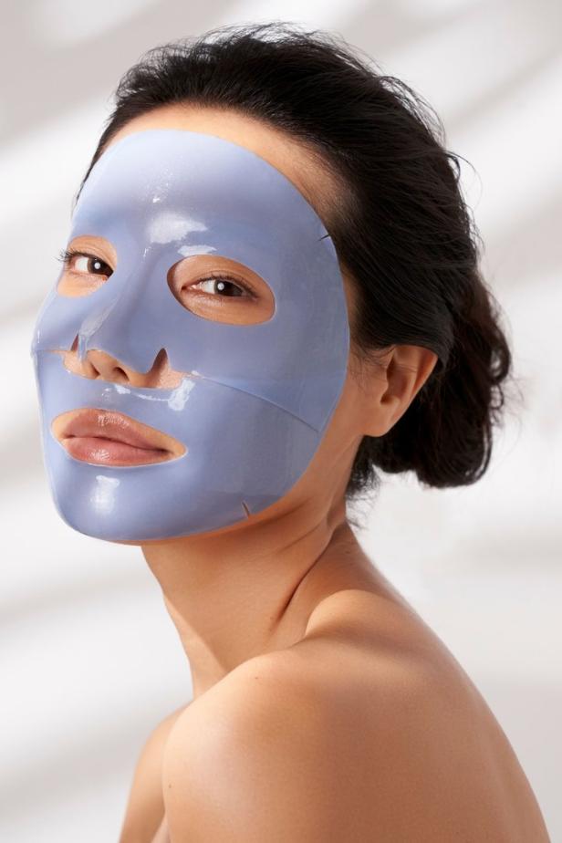 Eine Frau trägt eine blaue Tuchmaske auf ihrem Gesicht.