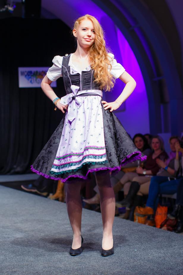 Eine junge Frau präsentiert ein Dirndl auf einem Laufsteg.