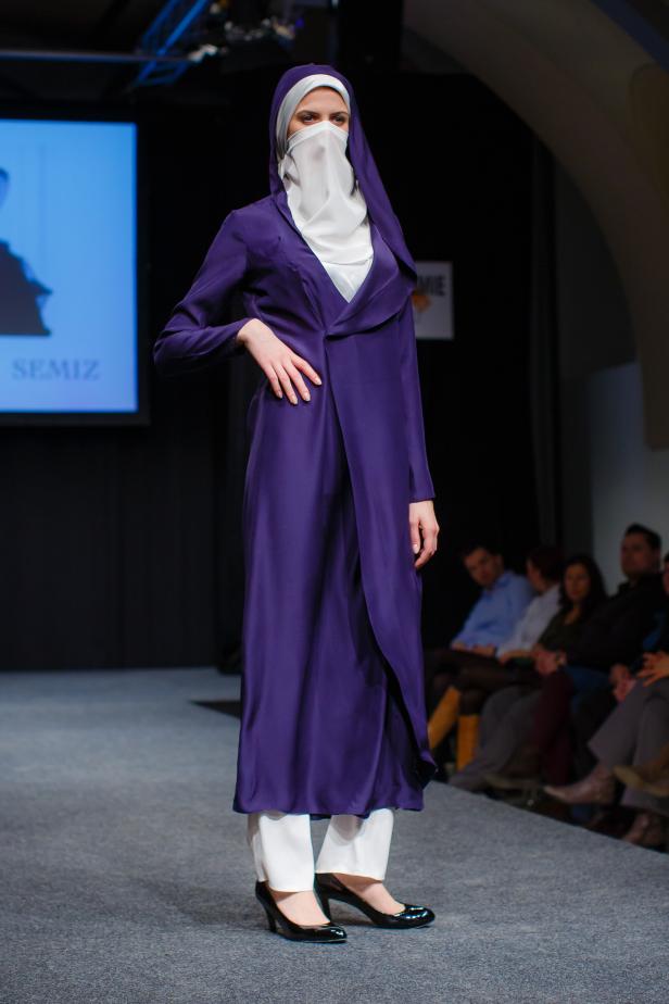 Eine Frau mit Hijab und langem, violettem Kleid auf einem Laufsteg.