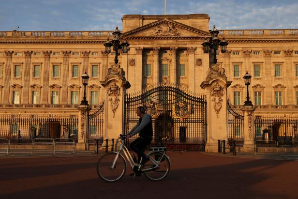 Ein Mann fährt mit dem Fahrrad vor dem Buckingham Palace.