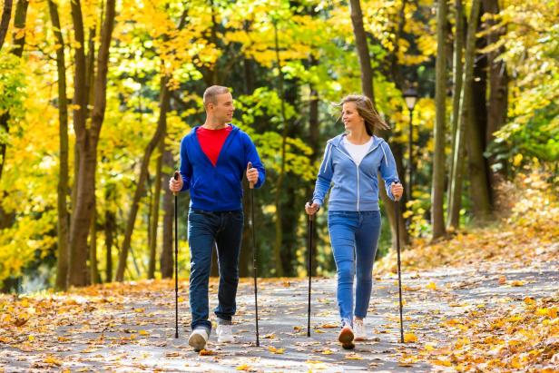 Ein Mann und eine Frau beim Nordic Walking in einem Park.