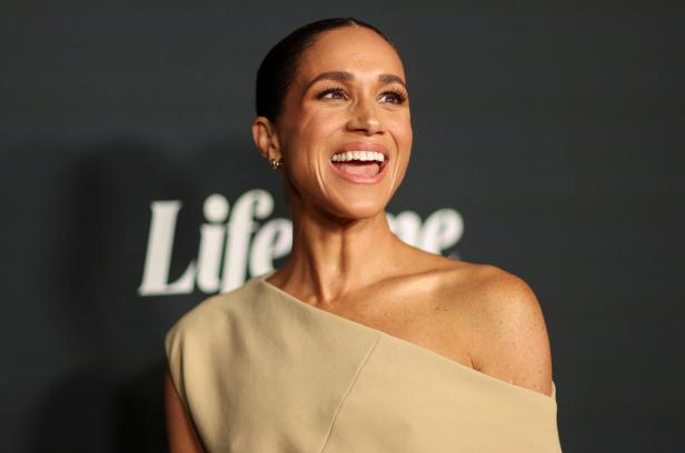 Herzogin Meghan lächelt vor einem „Lifetime“-Logo.