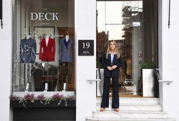 Eine Frau in einem Hosenanzug steht vor dem Eingang von „The Deck London“.