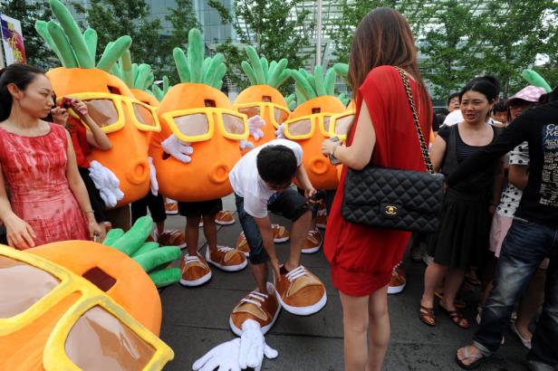 Eine Gruppe von Menschen in Karottenkostümen mit Sonnenbrillen steht im Freien.