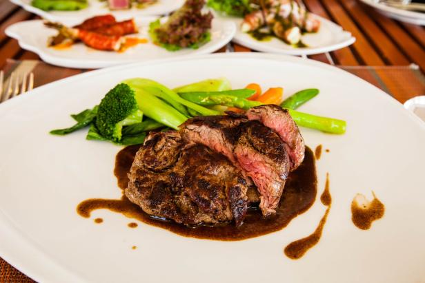 Ein Teller mit aufgeschnittenem Steak, Gemüse und Soße.