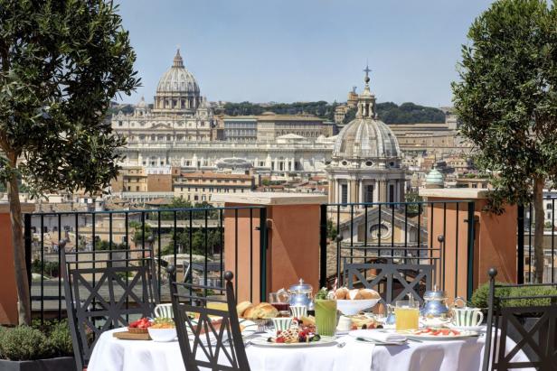 Ein gedeckter Frühstückstisch auf einer Dachterrasse mit Blick auf Rom und den Petersdom.