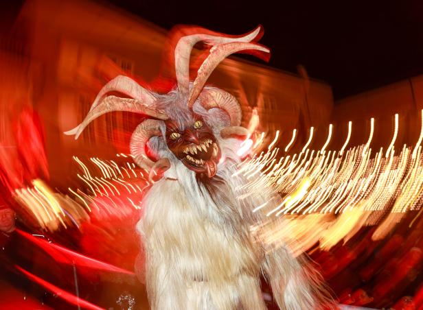 Ein Krampus mit Fell, Hörnern und einer furchteinflößenden Maske bei einem Umzug.