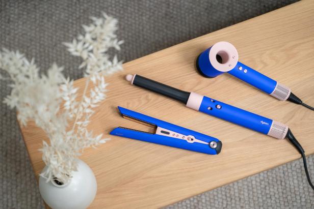 Dyson Haarpflegeprodukte in der Blue Blush Edition auf einem Holztisch.