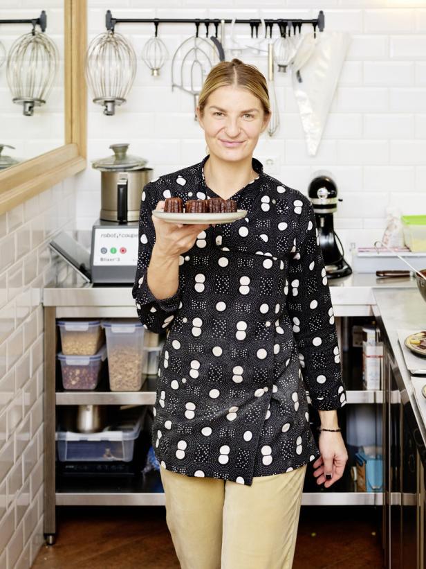Eine Frau präsentiert Canelés in einer professionellen Küche.