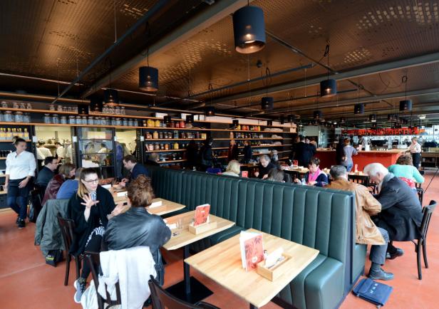 Gäste sitzen an Tischen in einem belebten Restaurant.