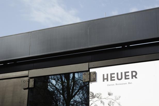 Das Schild des Restaurants „Heuer“ mit dem Hinweis „Garten. Restaurant. Bar.“.