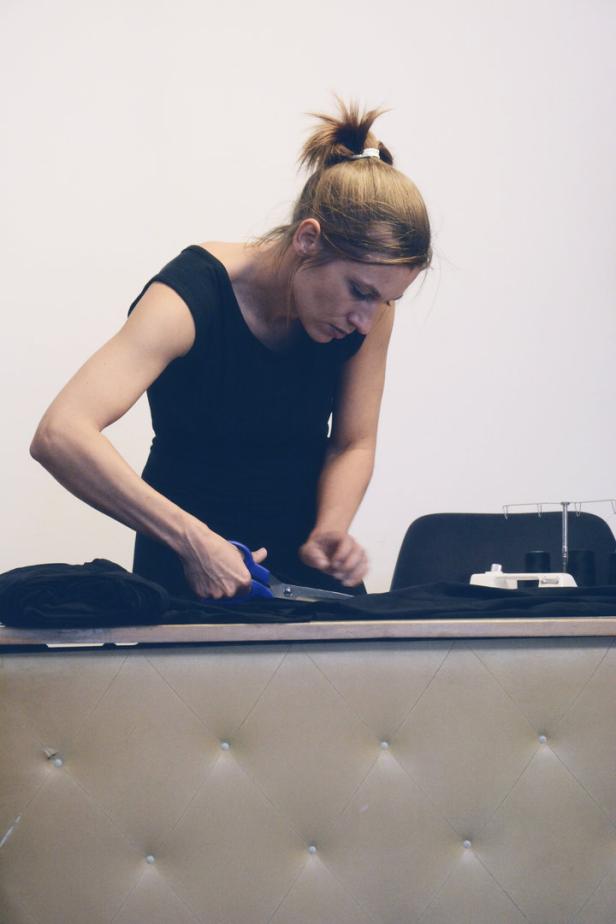 Sabine Aberle schneidet ein Stück schwarzen Stoff mit einer Schere.