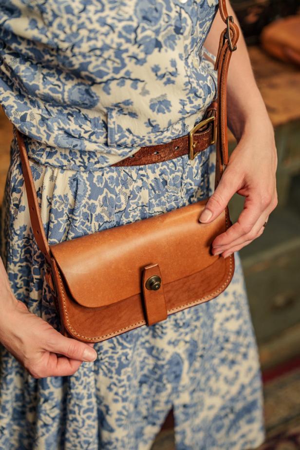 Eine Frau mit einem geblümten Kleid und einer braunen Ledertasche.