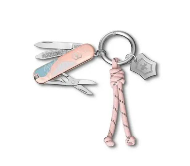 Ein Schweizer Taschenmesser mit rosa Griff, Klinge, Schere und einem Anhänger an einem Schlüsselring.