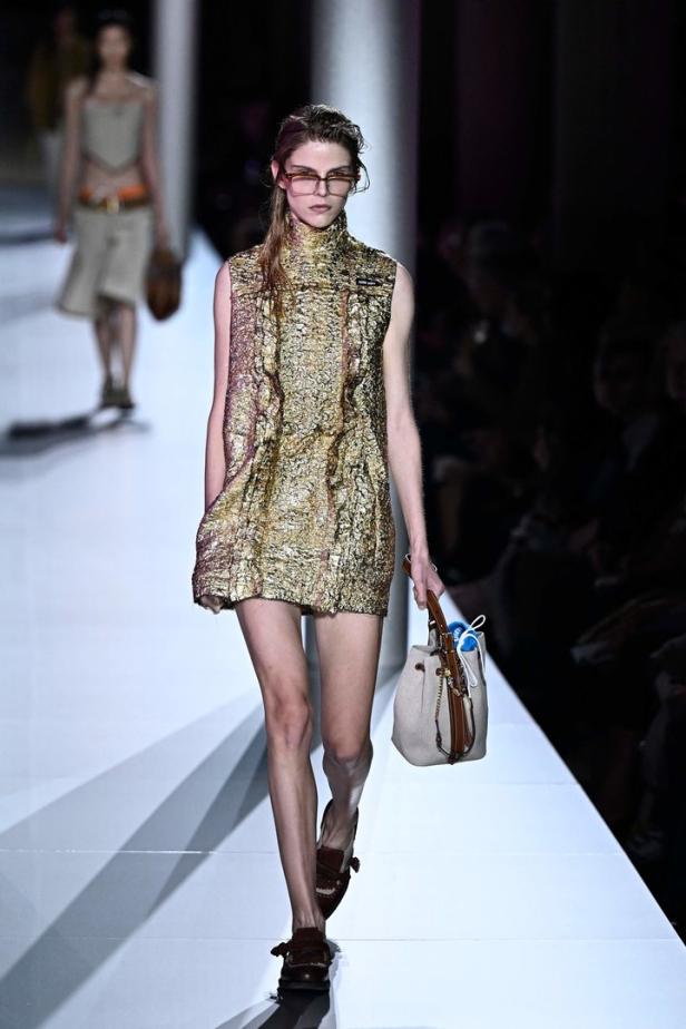 Ein Model präsentiert ein goldenes Minikleid von Miu Miu auf dem Laufsteg.