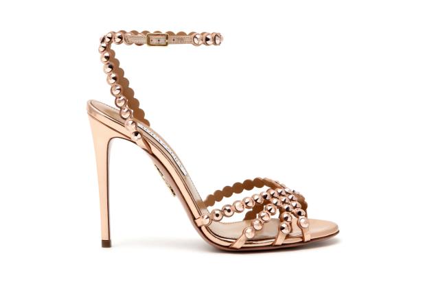 Ein goldener, hochhackiger Sandalenschuh mit Schmucksteinen auf weißem Hintergrund.