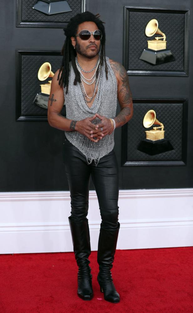 Lenny Kravitz auf dem roten Teppich in einem silbernen Oberteil, Lederhose und Stiefeln.