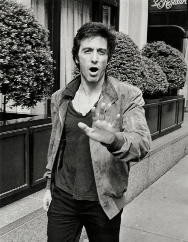 Al Pacino geht mit erhobener Hand auf der Straße entlang.