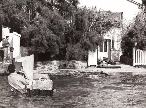 Ein Fotograf steht im Wasser und fotografiert ein Paar beim Sonnenbaden.