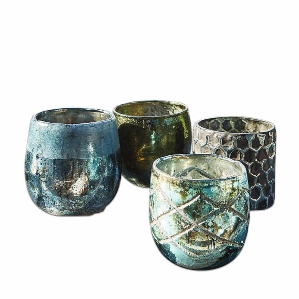 Vier dekorative Teelichthalter aus Glas in verschiedenen Farben und Mustern stehen auf einem weißen Hintergrund.