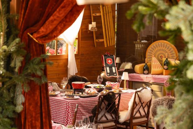 Ein gedeckter Tisch mit Fondue-Set in einer gemütlichen Hütte mit Schweizer Dekorationen.