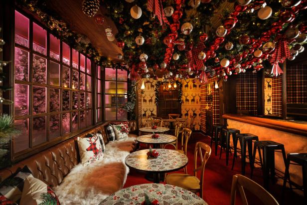 Ein weihnachtlich dekorierter Innenraum mit Tischen, Stühlen und einer Bar.