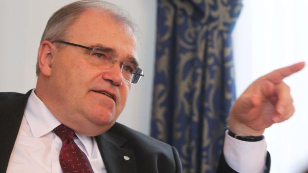 Ein Mann mit Brille, Anzug und Krawatte gestikuliert mit dem Finger.