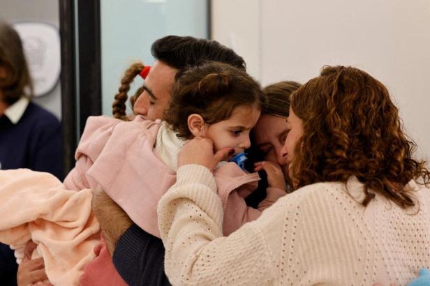 Aviv Asher, 2,5-year-old, her sister Raz Asher, 4,5-year-old, and mother Doron, react as they meet with Yoni, Raz and Aviv's father and Doron's husband, after they returned to Israel