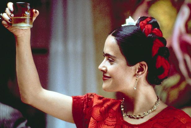 Salma Hayek als Frida Kahlo mit erhobenem Glas in der Hand.