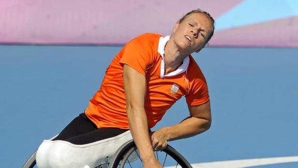 Eine Rollstuhlfahrerin in einem orangefarbenen Trikot bei einem Wettkampf.