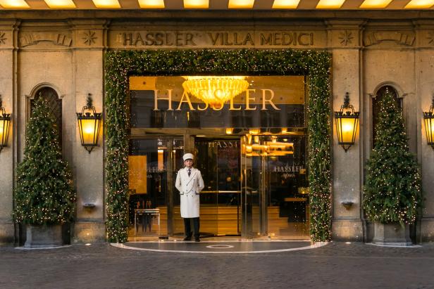 Ein Hotelpage steht vor dem weihnachtlich geschmückten Eingang des Hotels Hassler in Rom.