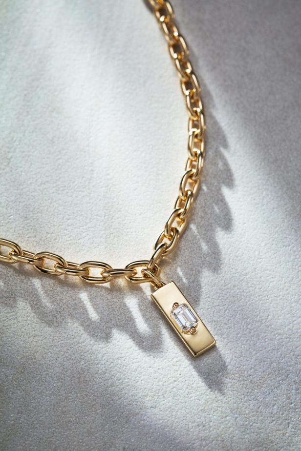 Eine goldene Halskette mit einem rechteckigen Anhänger und einem Diamanten darauf.