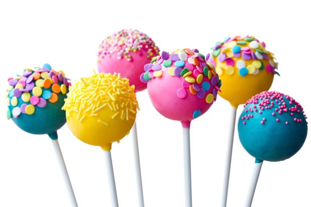 Mehrere bunte Cake Pops mit Streuseln auf weißen Stielen.