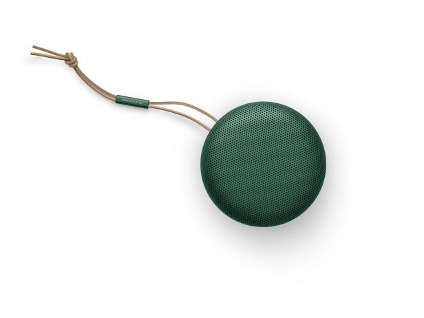 Ein runder, grüner Bluetooth-Lautsprecher von Bang & Olufsen mit einer beigen Trageschlaufe.