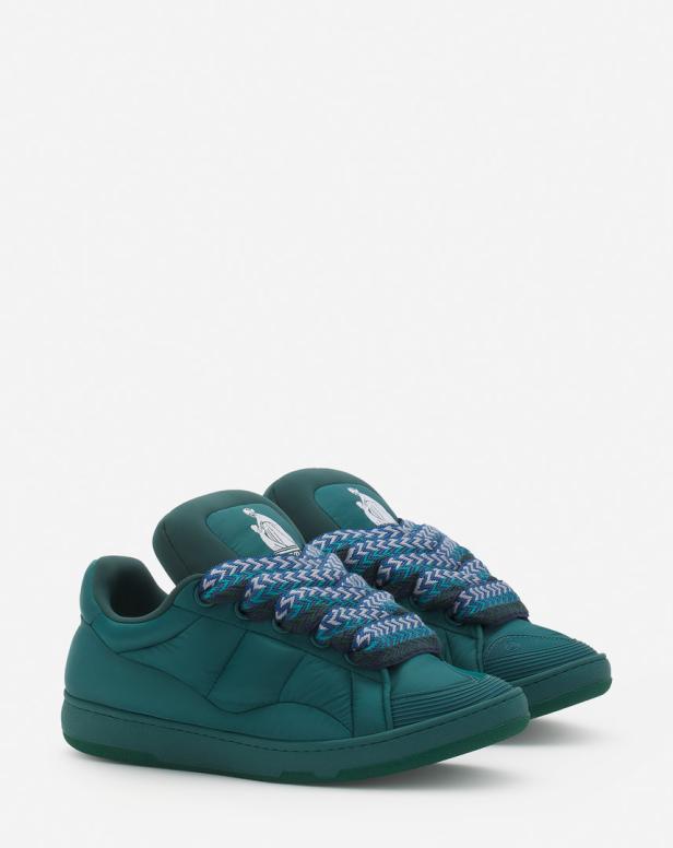 Ein Paar grüne Sneakers mit dicken, gemusterten Schnürsenkeln stehen auf einem weißen Hintergrund.
