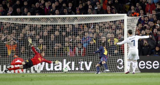 Lionel Messi schießt einen Elfmeter, während Cristiano Ronaldo zusieht.