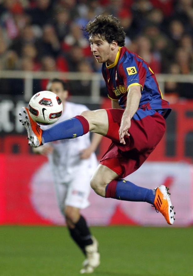 Lionel Messi springt, um einen Fußball zu treten.