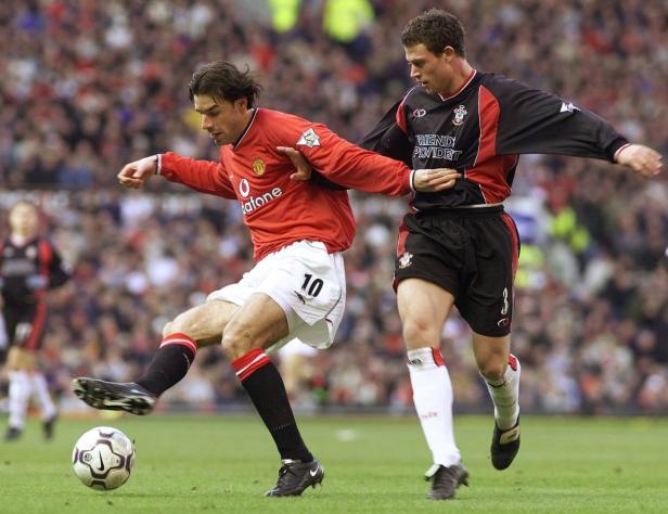 Ein Fußballspieler von Manchester United schießt den Ball, während ein Gegenspieler ihn verfolgt.